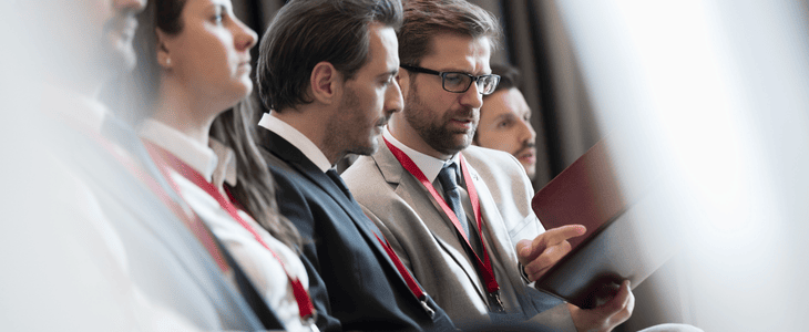 A group of leaders sit and listen intently at a conference
